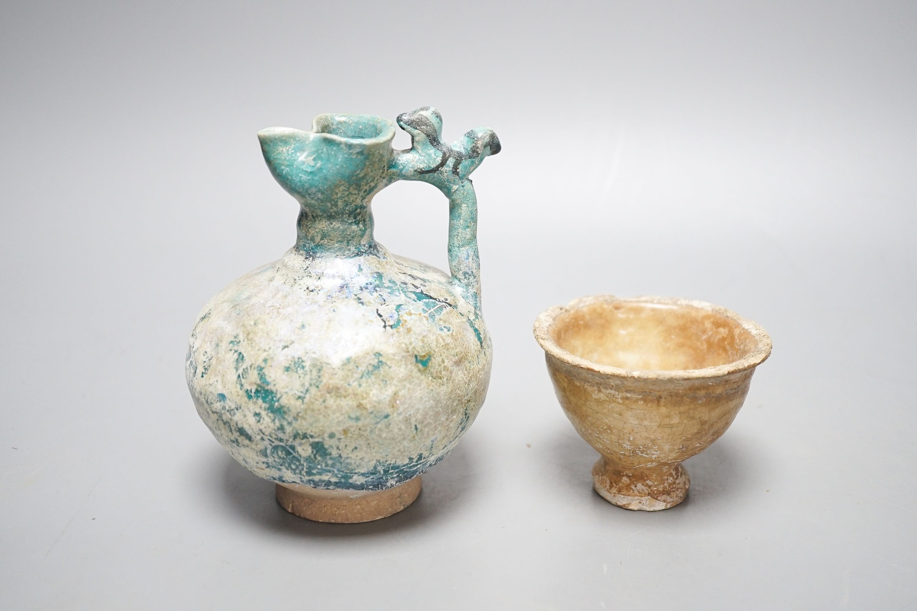 A Kashan turquoise glazed pottery ewer, 14th century, with mineral iridescence and an early Islamic pottery cup 14cm
